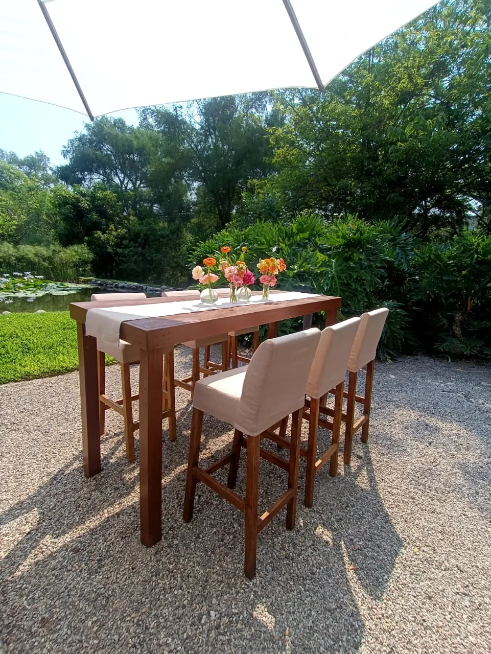Mesa alta de madera con bancos tapizados en jardín