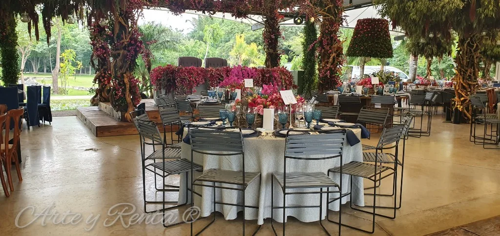 Banquete con mesas redondas, sillas oscuras y flores en tonos intensos
